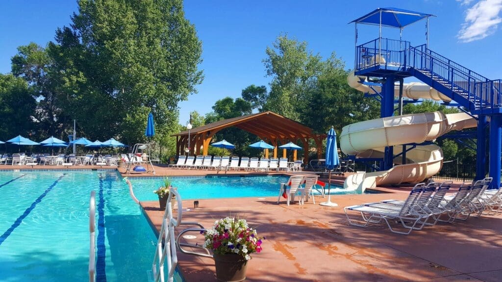 Outdoor pool with waterslide tower, lap lanes and shaded lounge chairs