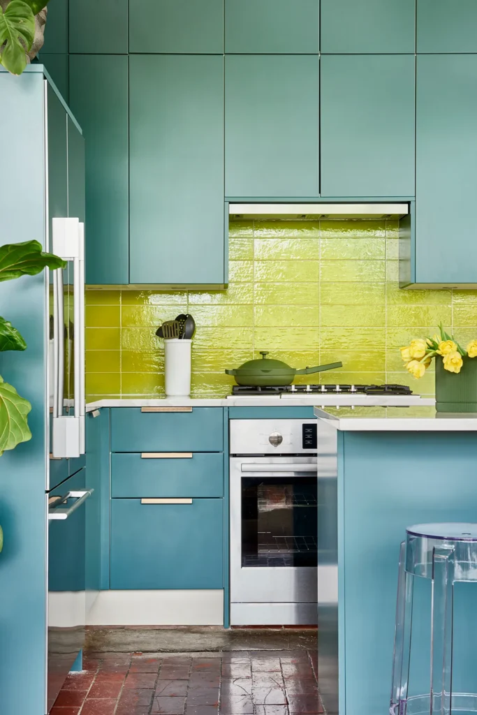 Teal kitchen cabinets with a glossy chartreuse tile backsplash
