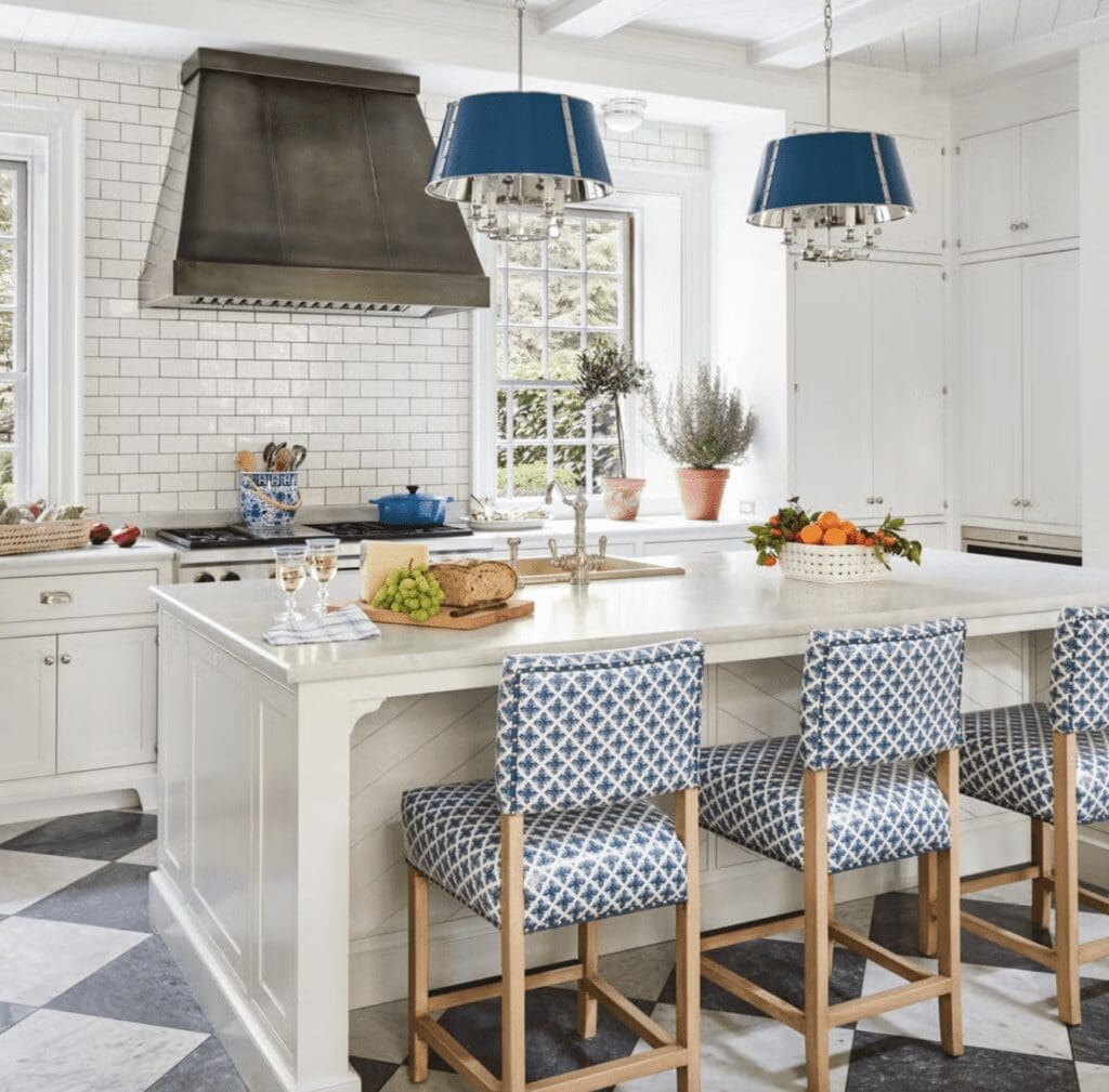 White kitchen with blue pendant lights and blue patterned barstools at the island