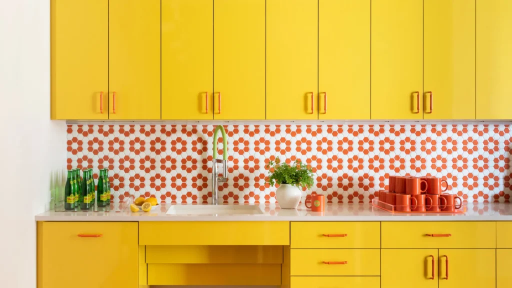 Bright yellow kitchen cabinets with an orange and white floral tile backsplash