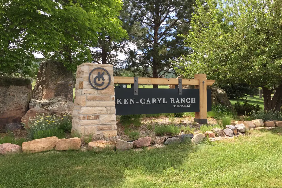 Ken Caryl Ranch The Valley entrance sign with stone pillar and trees